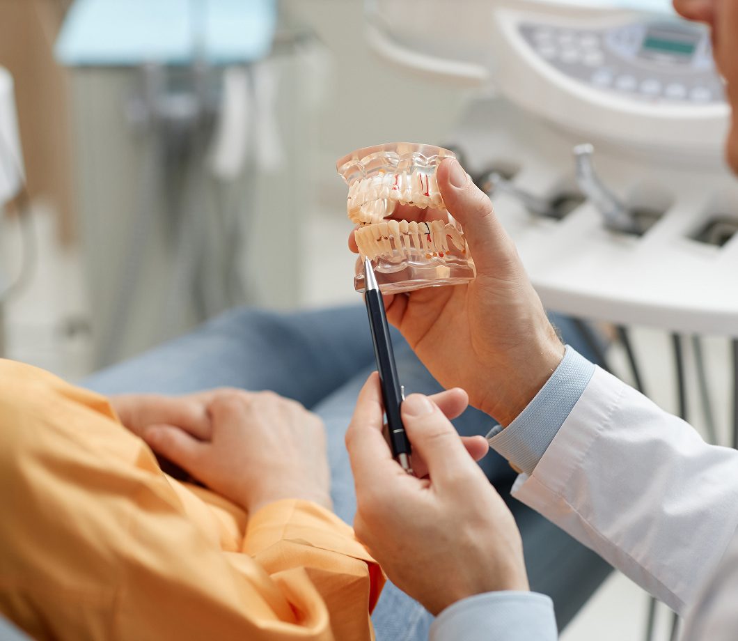 Surgeon using a dental model to explain implant candidacy