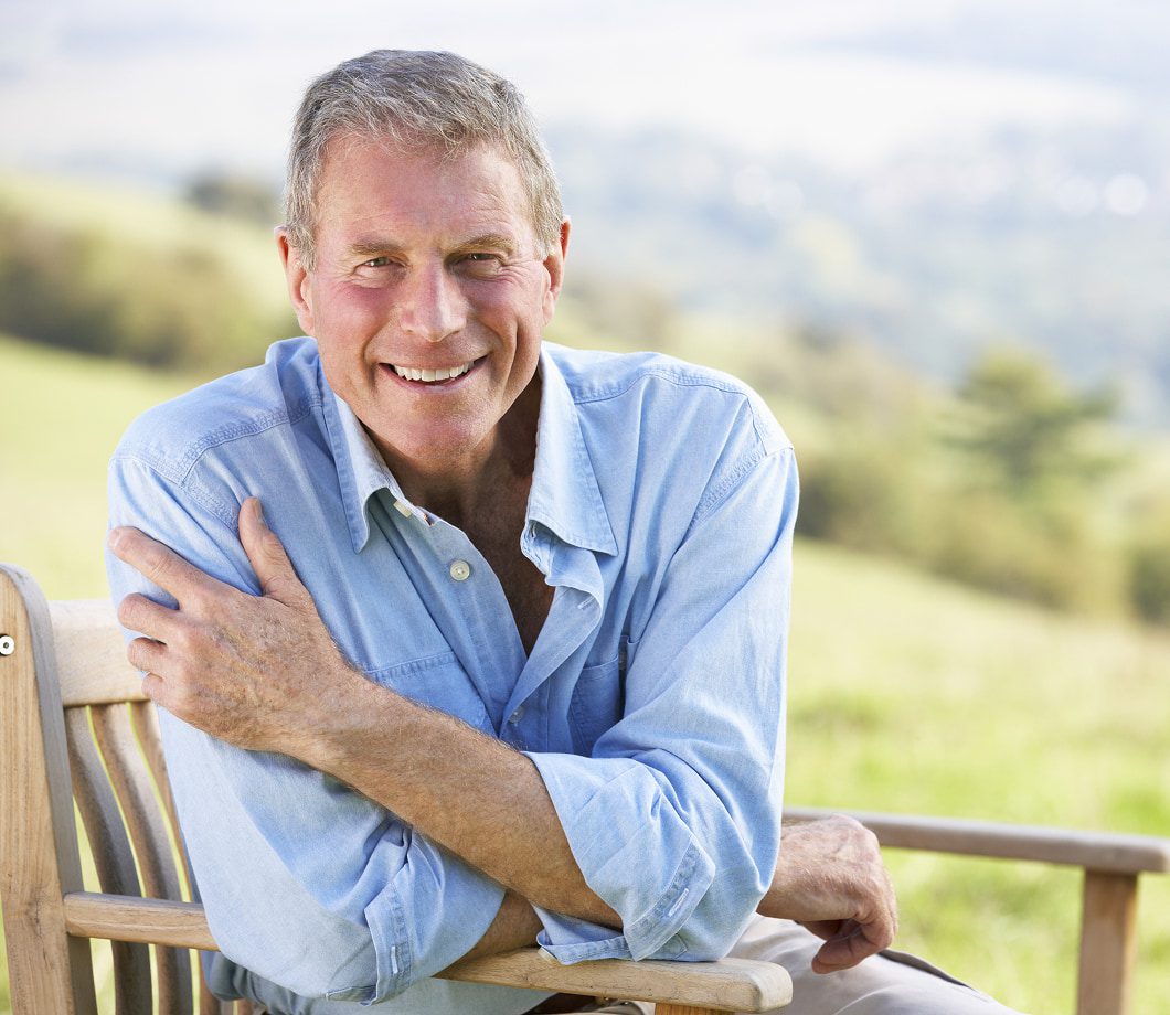 Smiling man relaxing outdoors after full mouth implant treatment